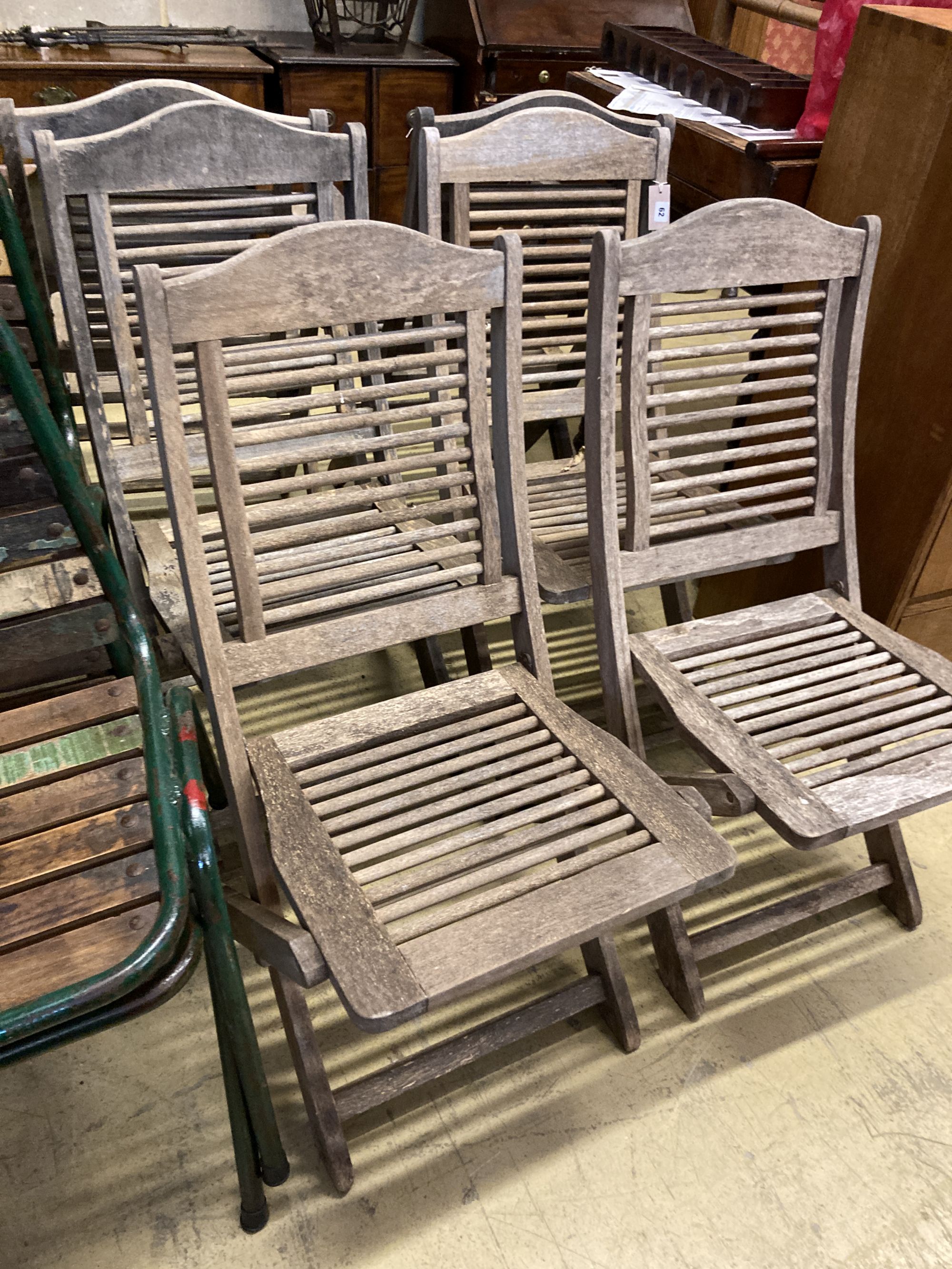 A set of six weathered teak folding garden chairs, two with arms